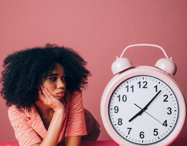 Woman looking at the pink alarm clock