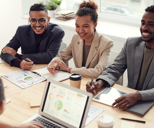 Photo of Three People Smiling While Having a Meeting